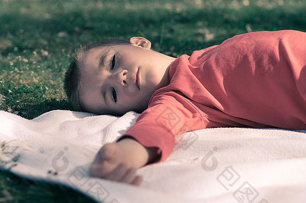 男孩躺在草地上毯子上的肖像。