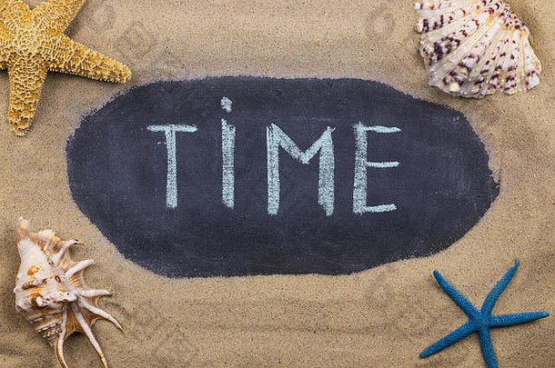 手写的粉笔在黑板上写下时间，躺在沙滩上的贝壳和海星中间。俯视图