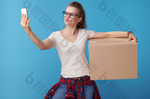 活跃的女人白色衬衫纸板盒子采取自拍智能手机蓝色的背景