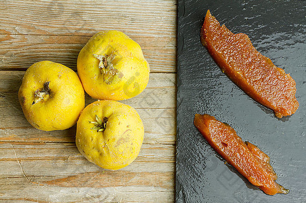 板岩板上的西班牙木瓜酱，木质背景上有三种木瓜果实