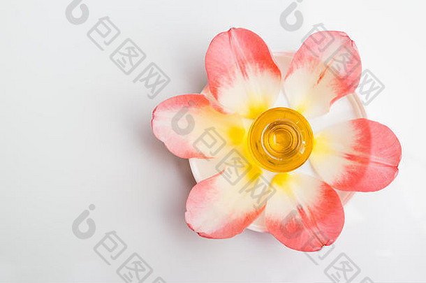 玫瑰香薰油。盘子上的滴管瓶，带有嫩粉色花瓣和花朵，俯视图。