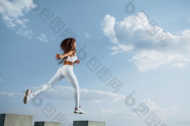 在天空中。穿着白色运动服的女跑步者正在健身