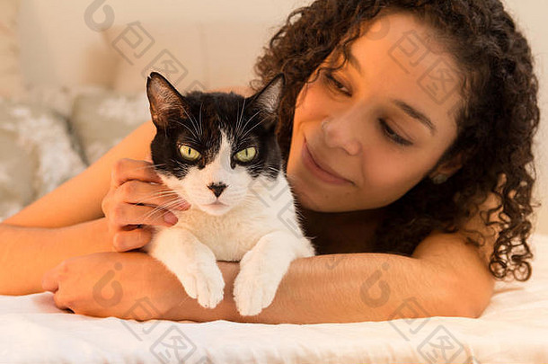 女主人在卧室里抱着她可爱的黑白相间的猫的特写镜头。爱护动物、宠物、关爱、宁静的理念。
