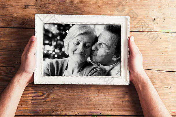 照片中手拿着老年夫妇的黑白照片