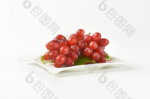 一束洗过的红葡萄放在白色的方形盘子上