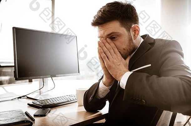 业务危机概念情感年轻的商人工作担心强调经理坐着办公室表格抓住脸手忙男人。