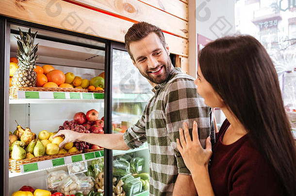 幸福的年轻夫妇站在杂货店挑选蔬菜
