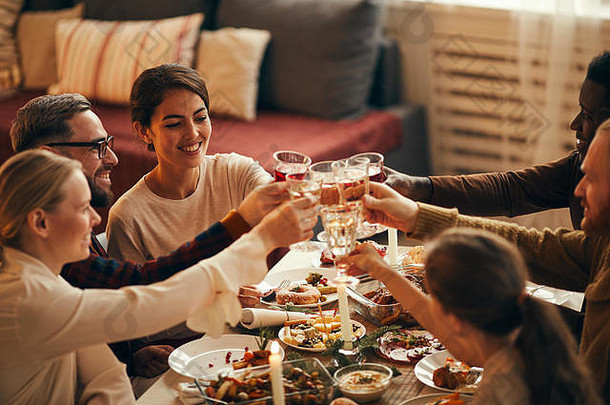 高角度观看优雅的年轻人在家享用圣诞晚餐时碰杯，空间