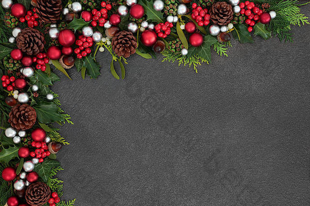 圣诞<strong>喜庆</strong>的背景<strong>边框</strong>，红色和银色的球形饰物，冬青树，槲寄生和冬季植物，灰色背景，<strong>带</strong>有空间。