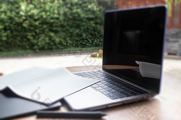 现代笔记本电脑在家中花园的木桌上，库存照片