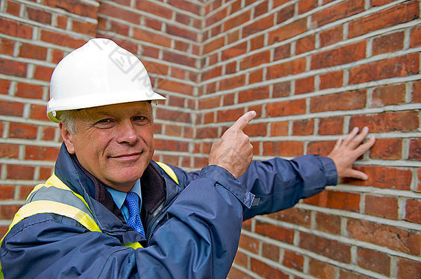 维护工程师在砖墙背景下的头肩视图。