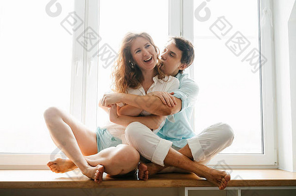 幸福的女孩和男人在家的窗户边拥抱。