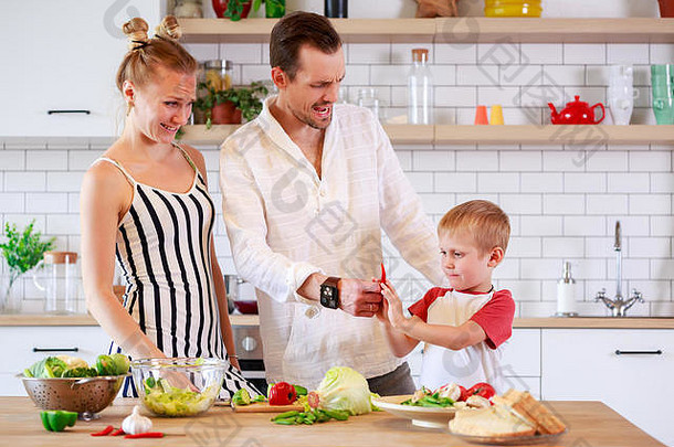 年轻的母亲、父亲和小儿子在厨房准备食物的画面