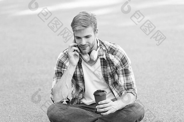 早晨的气氛。那个人坐在地上。戴着耳机的无忧无虑的学生。在线教育。听音乐。一个穿格子衬衫的男人在电话里讲话。学生放松和充电。咖啡带走。那个家伙喝咖啡。