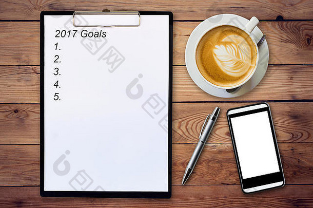 商业理念-俯视剪贴板，将2017年的目标、钢笔、咖啡杯和电话写在木桌上。