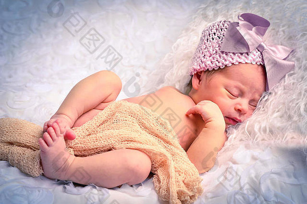 可爱的新生儿婴儿女孩睡觉白色皮毛枕头穿粉红色的<strong>针织帽</strong>大粉红色的弓挂网织物