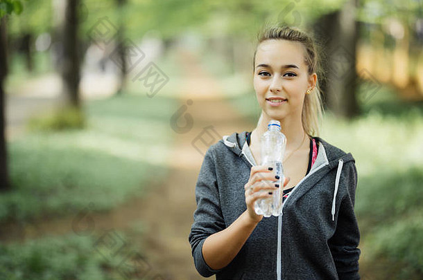年轻的金发女郎在慢跑和喝水后正在放松。