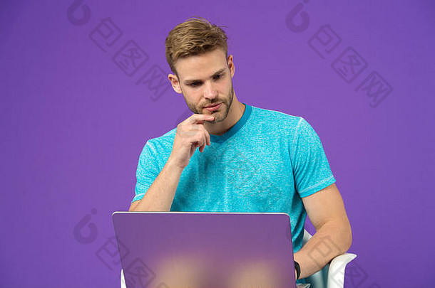 男人在紫色背景下用笔记本电脑工作。一个穿着蓝色T恤，电脑背景是紫色的家伙。网上冲浪和虚拟世界。博客或博客和博客。社交网络中的现代生活。