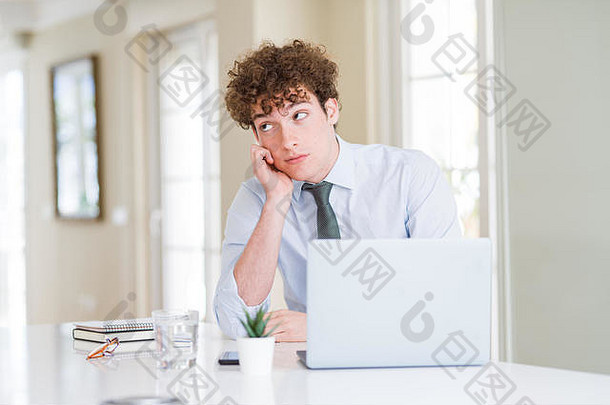 在办公室里用笔记本电脑工作的年轻商人，双臂交叉，看起来很疲惫，对抑郁症感到厌烦。