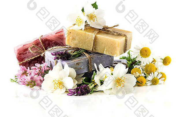 白色背景上有新鲜薰衣草、茉莉花、三叶草和洋甘菊花的肥皂条