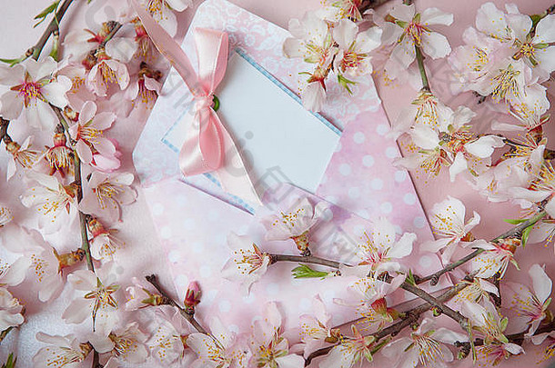 信封上印有粉红结的题字卡，粉红色背景上有开花的树枝