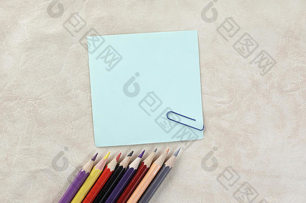 在纸背景上作笔记和彩色铅笔的一张纸