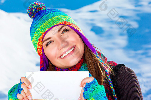 雪山背景上手握空白贺卡的快乐微笑女孩肖像，祝贺文字空间