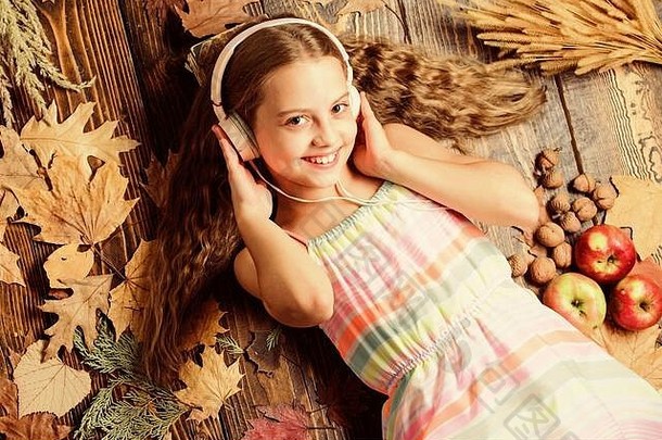 受秋天启发的声音和节奏。听音乐的小女孩。戴着立体声耳机的小女孩。以秋天为背景的可爱的音乐迷。可爱的孩子喜欢用耳机播放音乐。