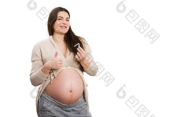 快乐的孕妇竖起大拇指，在白色背景上孤立地拿着香烟作为戒烟的概念