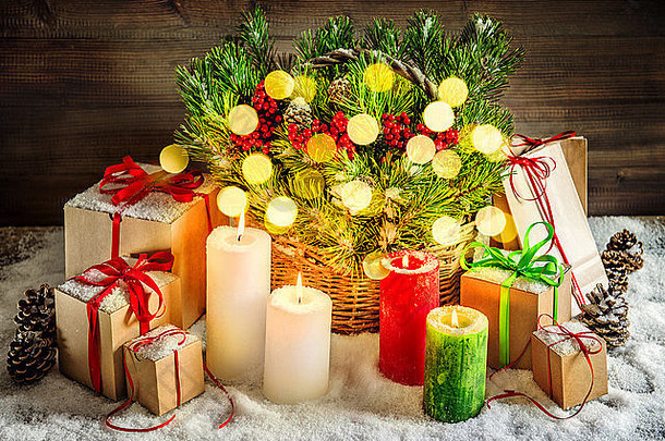 圣诞装饰燃烧蜡烛和礼品盒。篮子里的圣诞树枝。