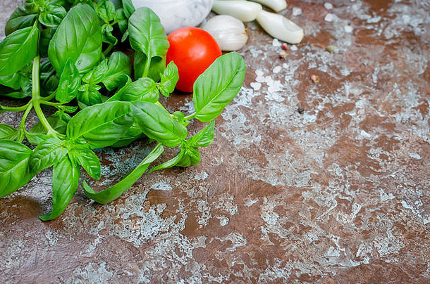 青罗勒、西红柿、葱、大蒜、盐和香料，以深色石头为背景。俯视图，空间。