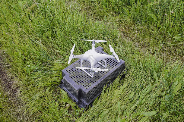 草地上一个塑料盒子上的四翼机。准备起飞。