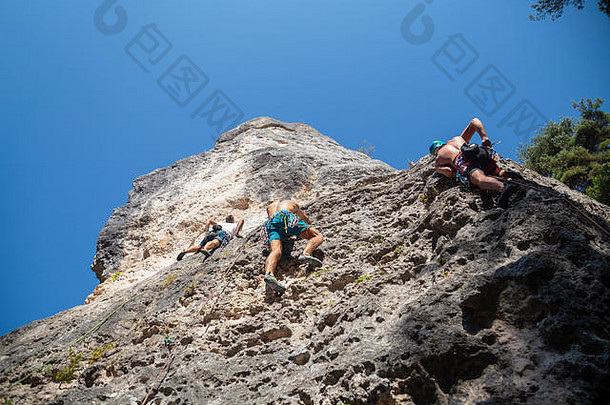 三个攀岩朋友早上爬一块大岩石