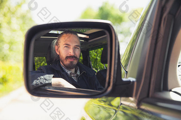 严肃的亚洲男人，一个司机，在车镜里看，户外夏日肖像