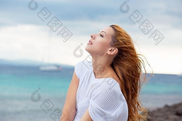 女人在海边放松，在海边的风中梳着头发，享受夏日的<strong>自由</strong>。夏季<strong>旅<strong>游</strong>度假的混血西班牙裔白人女孩