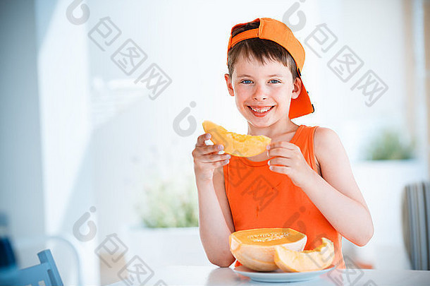 可爱的小男孩手里拿着切成片的橙色哈密瓜