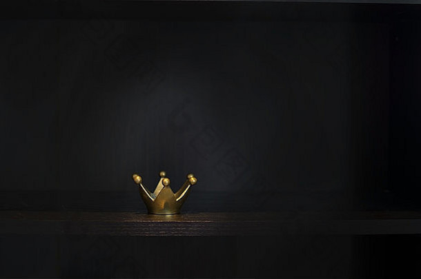 深色背景上的金色金属皇冠，带有空间，明暗对比风格。