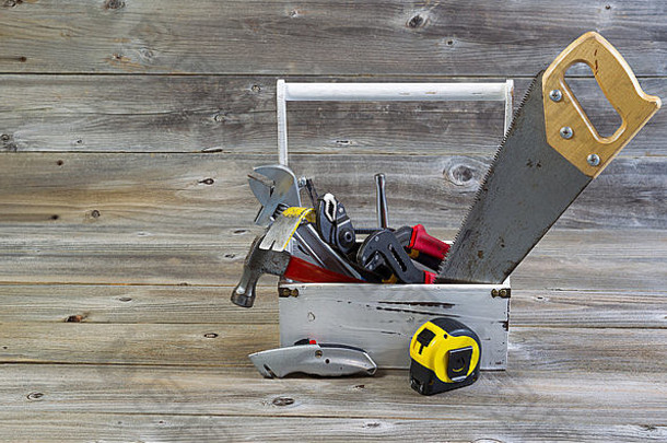 一个旧工具架的水平视图，该工具架包含基本的家用维修工具，位于粗糙木板上