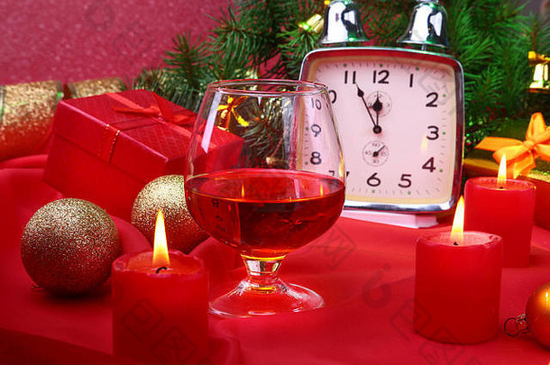 圣诞钟，装有白兰地或威士忌和蜡烛的玻璃杯。新年装饰，包括礼品盒、圣诞球和圣诞树。庆祝新年的概念。