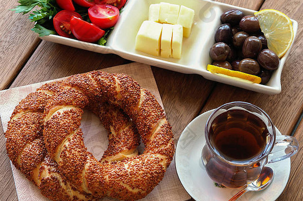 木制餐桌上的土耳其百吉饼、茶和早餐盘。西红柿、奶酪、橄榄