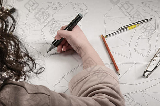女设计师画了一幅工作图。玩具设计师的工作场所。马克笔、尺子、钢笔和铅笔在图纸上