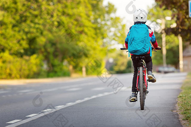 在学校附近的公园里，一个背着背包骑自行车的孩子
