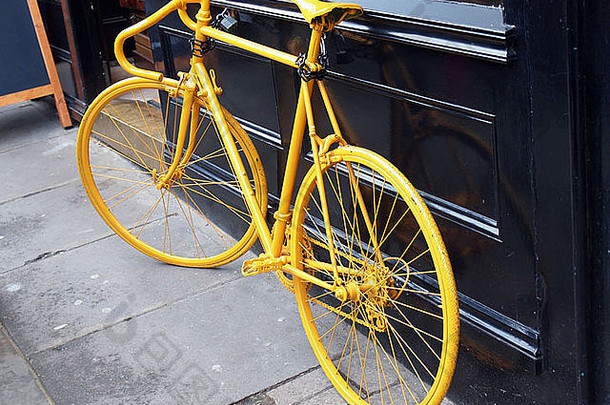 咖啡店橱窗上旧黄色自行车的照片
