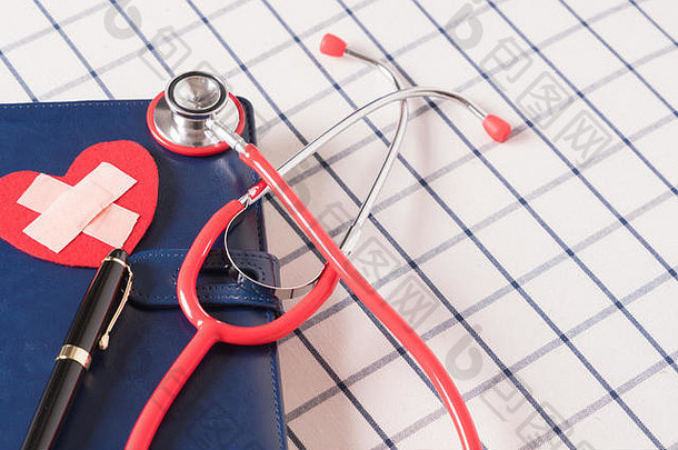 世界卫生日医疗保健和医疗概念蓝色每日笔记本上的红色听诊器和红色心形