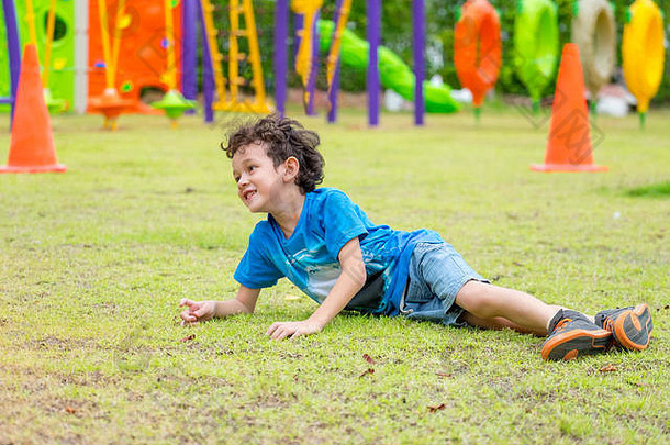 孩子们在学校的儿童游乐场玩得很开心，孩子们跑来跑去，摔倒在草地上。返校户外活动