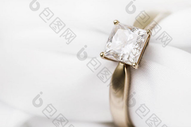 真丝面料上镶有大钻石的金色结婚戒指，有空间，特写