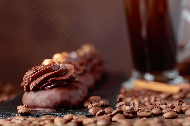 木桌上放着榛子巧克力甜点和奶油咖啡。咖啡豆和肉桂棒散落在桌子上。