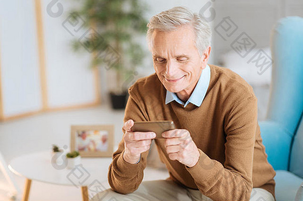 微笑的老人看着智能手机上的照片