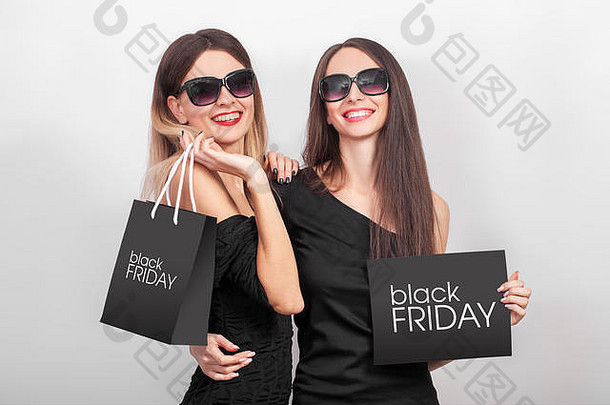 购物黑色星期五假期，两名妇女在灯光背景下拿着黑色袋子