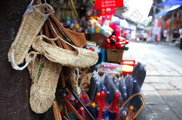 中国一条古老小巷里的中国传统手工艺品：草鞋、伞。背景颜色是红色。